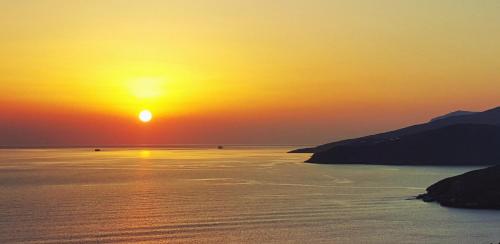 a sunset over a body of water with the sun setting at Avissalou Apartments in Agios Romanos