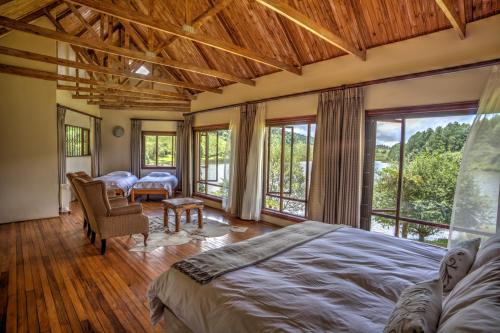 a bedroom with a large bed and a balcony at Pavetta Country House in Magoebaskloof