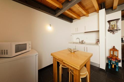 eine Küche mit einem Holztisch und einer Mikrowelle in der Unterkunft Antiga Casa do Boi in Viseu