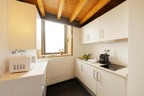 a kitchen with white cabinets and a microwave at Antiga "Casa do Porco" in Viseu