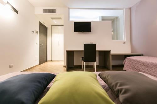 a bedroom with two beds and a desk with a television at I Love Puglia in Conversano