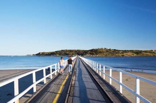 two people walking on a pier on the beach at NRMA Victor Harbor Beachfront Holiday Park in Victor Harbor