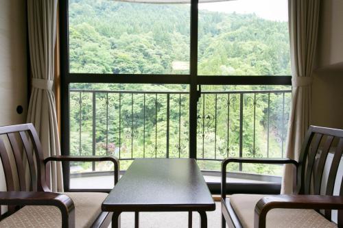 a table and chairs in front of a large window at Okuhida Garden Hotel Yakedake in Takayama