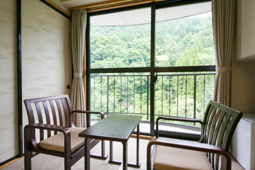 a room with a table and chairs and a large window at Okuhida Garden Hotel Yakedake in Takayama