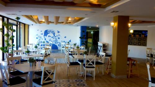 a dining room with tables and white chairs at Hotel Corona Plaza in Rosarito