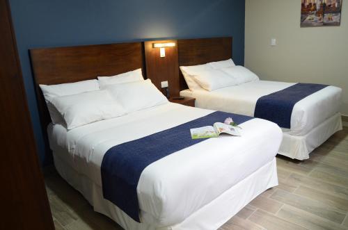 two beds in a hotel room with white sheets at Hotel San Agustin Plaza in Latacunga