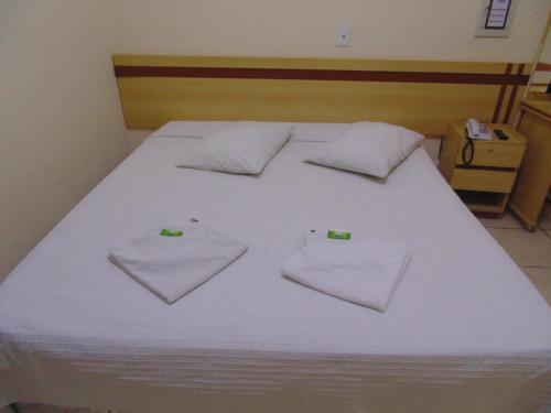 a bed with white sheets and pillows on it at Hotel Makarena in Três Corações