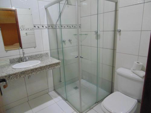 a bathroom with a glass shower and a toilet at Hotel Makarena in Três Corações