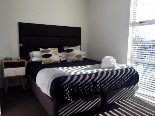 Schlafzimmer mit einem Bett mit einem schwarzen Kopfteil und Kissen in der Unterkunft Merivale Apartments in Christchurch