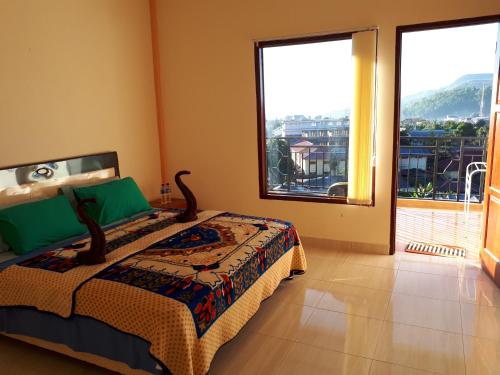 a bedroom with a bed and two large windows at Bajawa-Roo Hotel in Bajawa