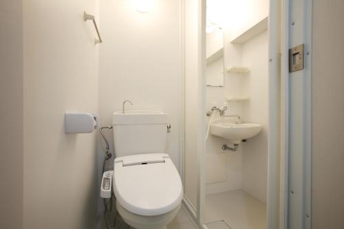 La salle de bains blanche est pourvue de toilettes et d'un lavabo. dans l'établissement Kurashiki Global Hotel, à Kurashiki