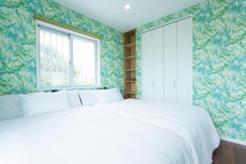 a bedroom with a white bed and green wallpaper at Suite villa Yagaji in Nago