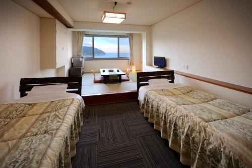 石巻市にあるSimamegurinoyado Sakaiのベッド2台と窓が備わるホテルルームです。