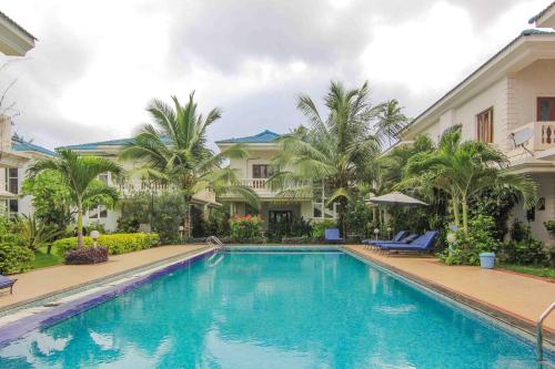 uma piscina em frente a uma casa com palmeiras em Rainforest - Casa Azure 5 Min walk to the beach em Calangute