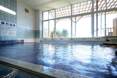 a swimming pool with blue water in a building at Simamegurinoyado Sakai in Ishinomaki