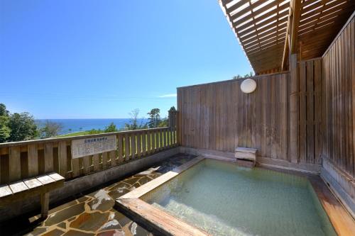 a hot tub on a deck with a wooden fence at Simamegurinoyado Sakai in Ishinomaki