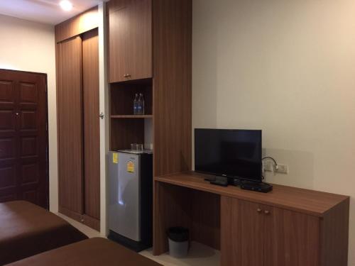 um pequeno quarto com uma televisão e um frigorífico em The Nine Mansion em Ubon Ratchathani