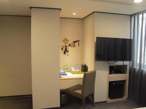 a room with a desk with a chair and a tv at Energy Inn in Taipei