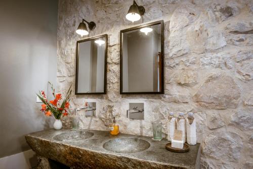 a stone bathroom with a sink and two mirrors at Topas Ecolodge in Sa Pa