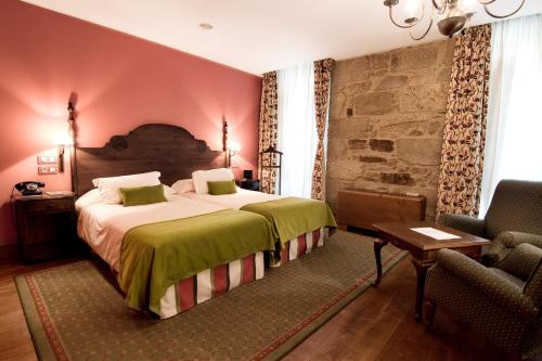 a bedroom with a large bed and a chair at Hotel Virxe da Cerca by Pousadas de Compostela in Santiago de Compostela