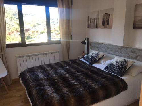 1 cama grande en un dormitorio con ventana grande en Apartamento Ezcaray con Piscina, en Zorraquín