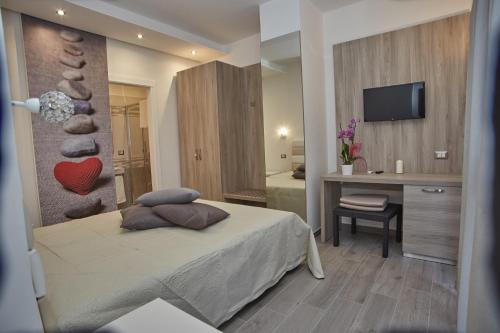 Schlafzimmer mit einem Bett, einem Schreibtisch und einem TV in der Unterkunft Carpe Diem in Peschici