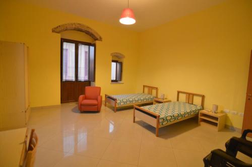 パキーノにあるTerrazza Vittorio Emanueleのベッド2台とオレンジの椅子が備わる客室です。