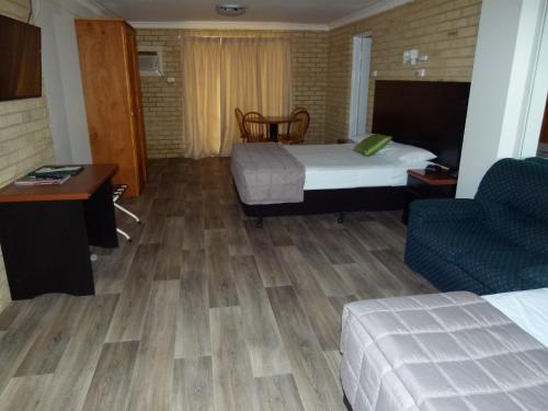 a hotel room with two beds and a desk and a chair at Lismore Wilson Motel in Lismore