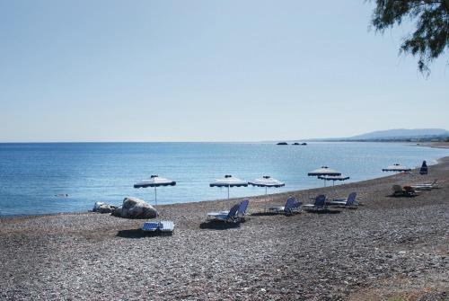 a beach with chairs and umbrellas and the water at Petroto Villas in Kiotari