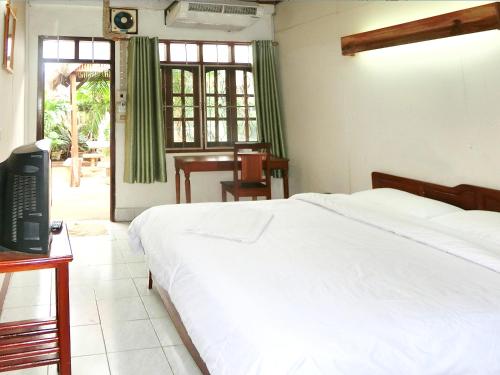a bedroom with a bed and a desk and a television at Villa Sisavad Guesthouse in Vientiane