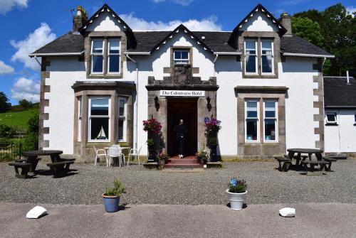 un gran edificio blanco con bancos delante en The Colintraive, en Colintraive