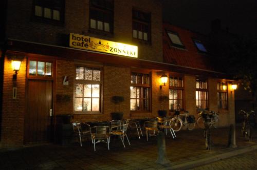 a hotel cafe with tables and chairs outside at night at Hotel Cafe 't Zonneke in Oosterhout