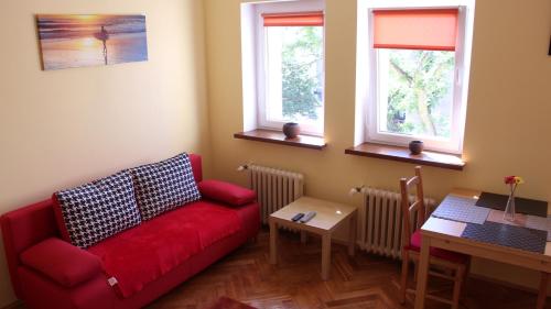 グディニャにあるApartament Słonecznyのリビングルーム(赤いソファ、テーブル付)