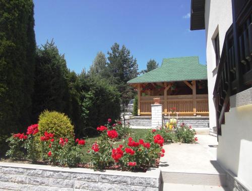 a garden with red flowers and a gazebo at Vila IV in Zlatibor
