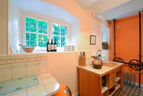 une cuisine avec évier et une fenêtre avec bouteilles de vin dans l'établissement Le Bois de Rome, à Conches-en-Ouche