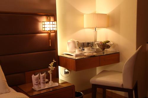 a room with a bed and a chair and a lamp at Middleton Inn in Kolkata