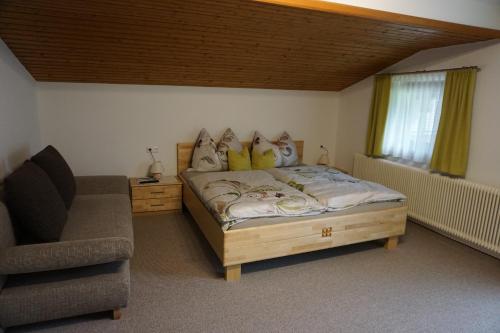 a bedroom with a bed with a chair and a couch at Habachschmied Familie Gruber in Bramberg am Wildkogel