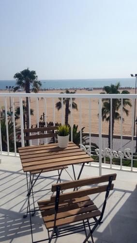 a wooden table and bench on a deck overlooking the beach at Sol Playa in Valencia