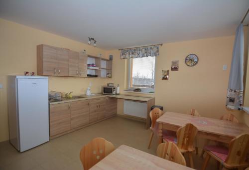 una cucina con un tavolo e un frigorifero e un tavolo e sedie di Vila Kamah a Tatranská Lomnica
