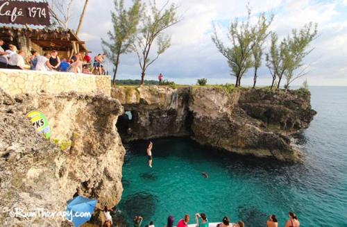 a group of people swimming in a cave in the ocean at T&T - Tatty and Tony Guesthouse in Negril