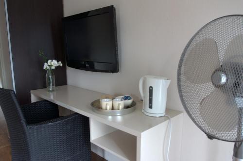 a room with a desk with a tv and a fan at B&B Posthoorn in Hoorn
