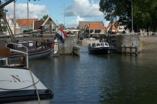 two boats are docked in a river with houses at B&B Posthoorn in Hoorn