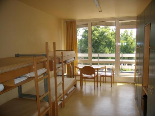 een slaapzaal met stapelbedden, een tafel en een raam bij Jugendgästehaus St.-Michaels-Heim in Berlijn