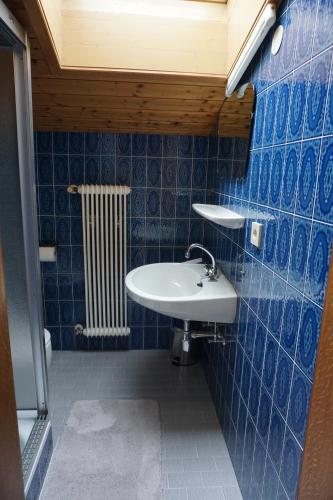 baño con lavabo y pared de azulejos azules en Habachschmied Familie Gruber, en Bramberg am Wildkogel