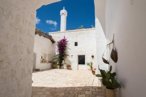 an alley with a white building with a tower at Masseria Le Cerase in Conversano