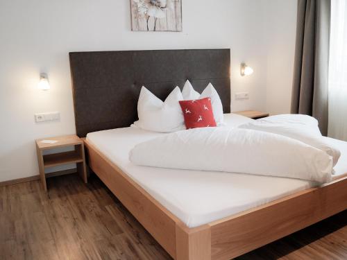 a bedroom with a large bed with white sheets and red pillows at Pension Apartment Erna in Resia