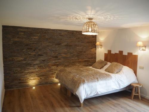 a bedroom with a large bed and a stone wall at La Balade du Ricochet in Tenneville