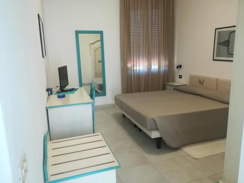 a bedroom with a bed, desk and a television at Hotel Nido D'aquila in La Maddalena