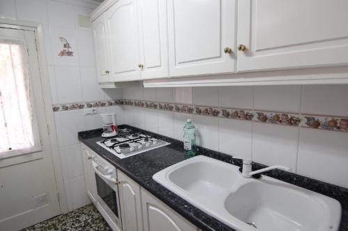 Maryvilla 224 في كاليبي: مطبخ أبيض مع حوض وموقد