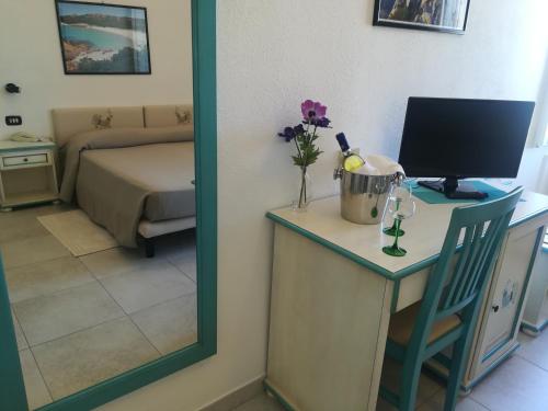 a room with a desk with a vase of flowers on it at Hotel Nido D'aquila in La Maddalena